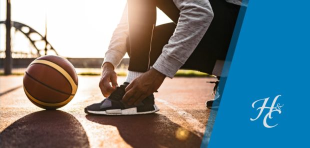 Man tying his shoe with basketball nearby on outdoor court